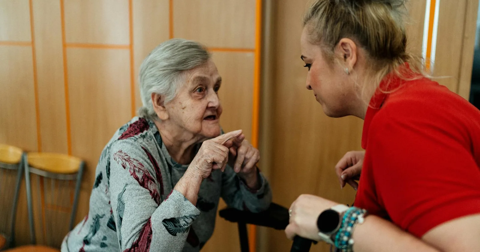 An elderly woman and her caregiver sitting together in warm conversation.