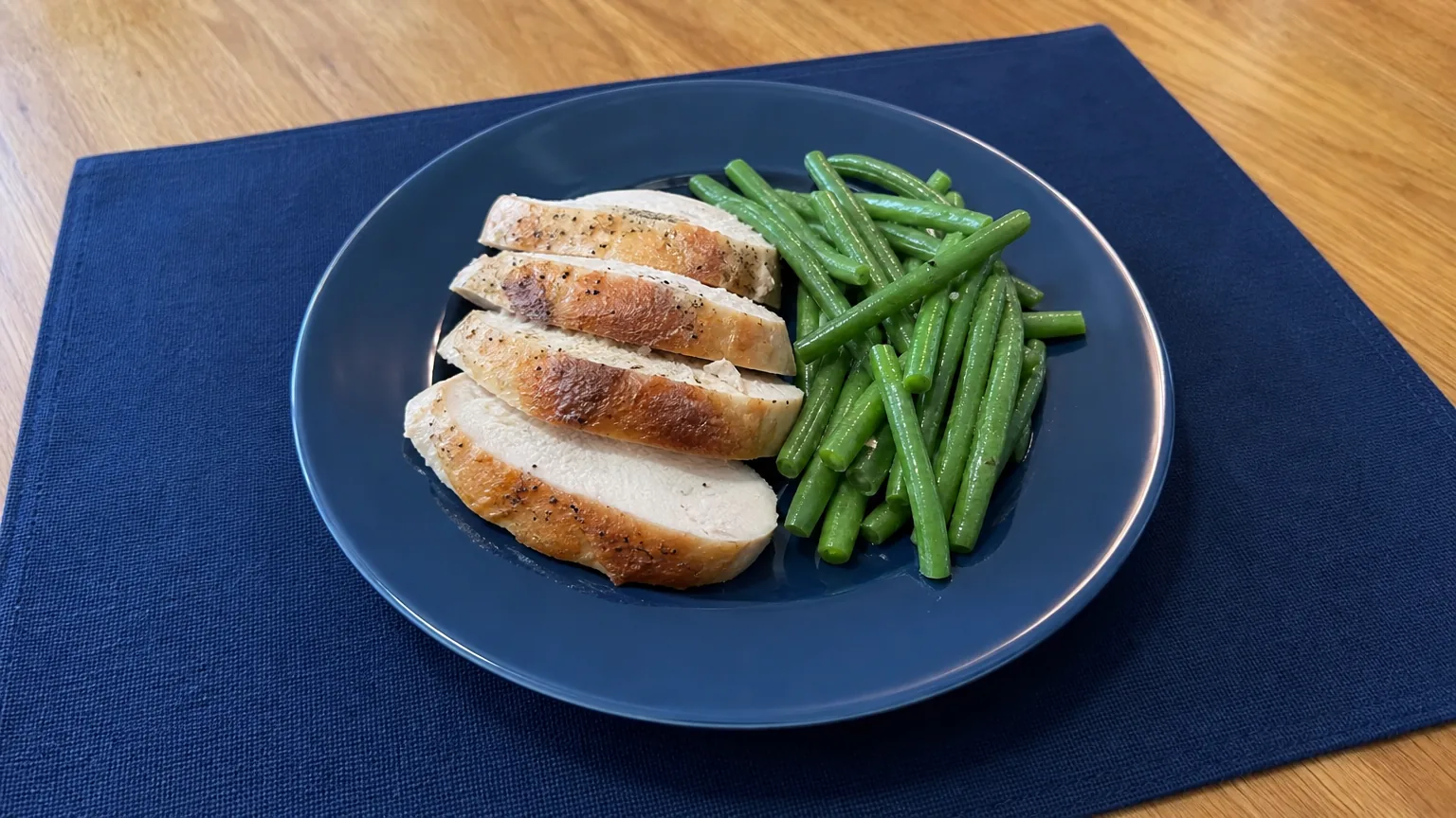 Blue plate of sliced chicken and green beans