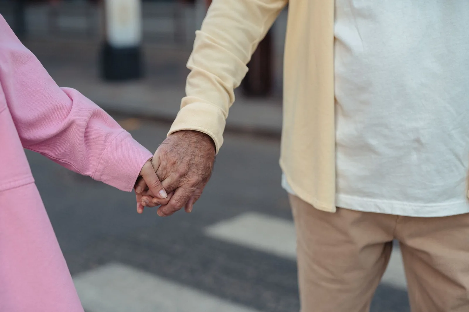 Two older people holding hands crossing a street