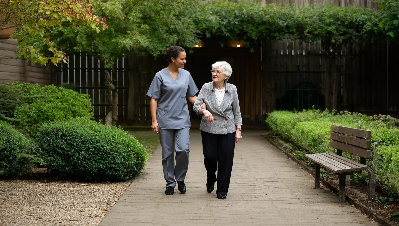 A care aide walking beside an older woman in a garden