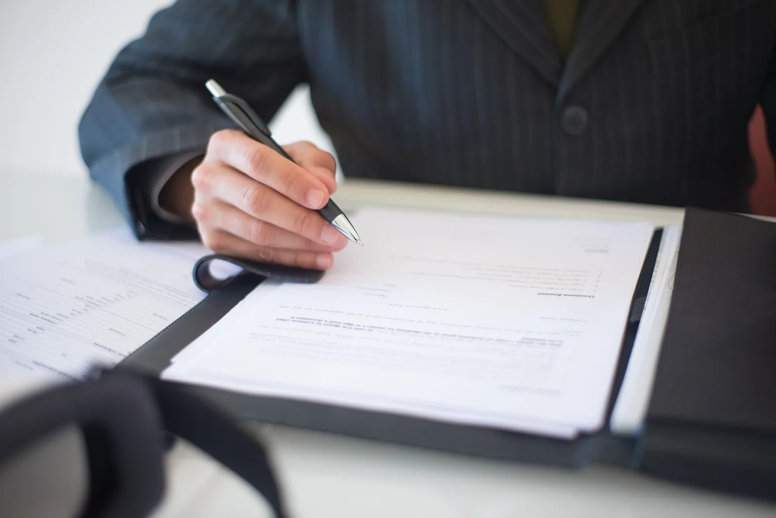 A hand signing a document with a pen